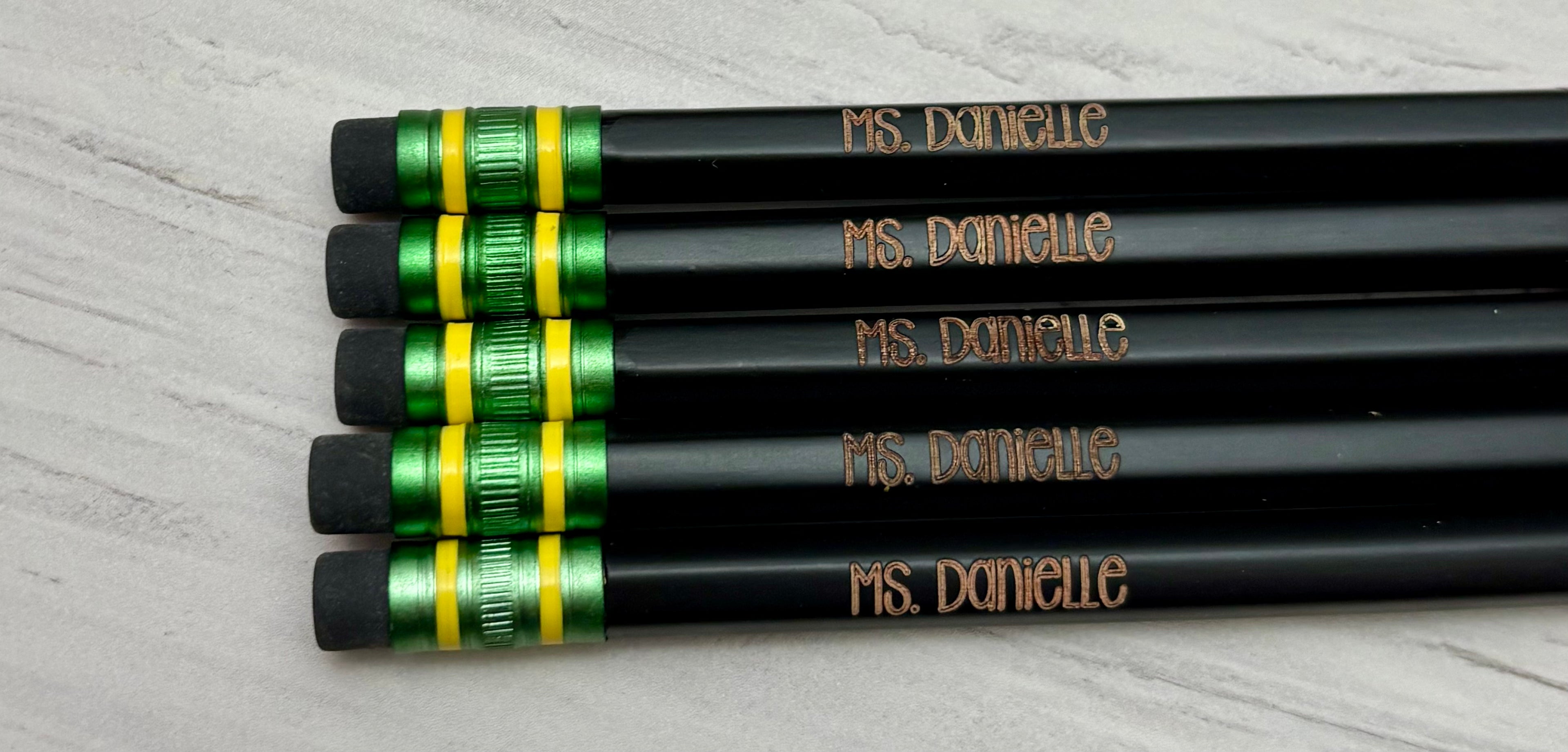 Five black pencils customized with a name.