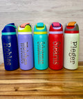 Stainless steel water bottles in different colors with custom names engraved vertically on the front. 