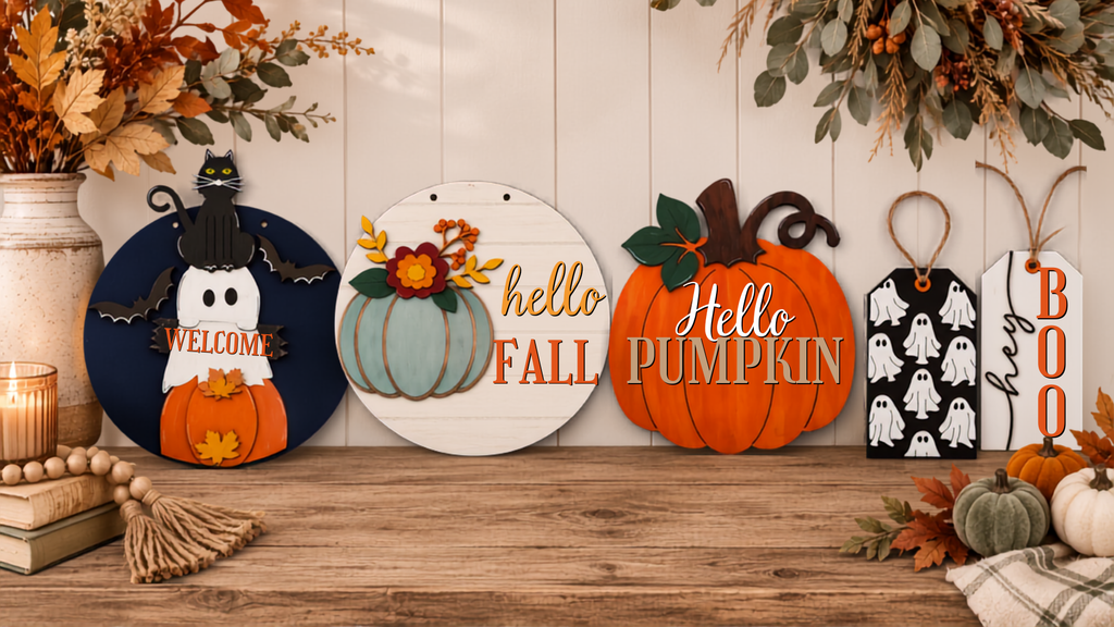 A set of four decorative autumn-themed wooden signs displayed on a rustic wooden table against a white wood-paneled wall.