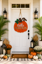 A decorative orange pumpkin-shaped sign with the words 'Hello Pumpkin' hangs on a white front door. 