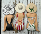 Three decorative figures of women in swimsuits with hats.